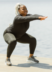 An overweight woman smiling and exercising by the water